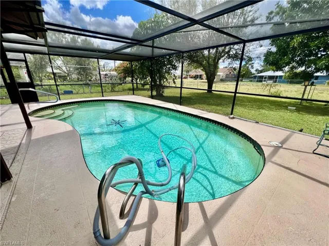 Outdoor pool with screen enclosed in ground pool.  enclosure, a lawn, and a patio