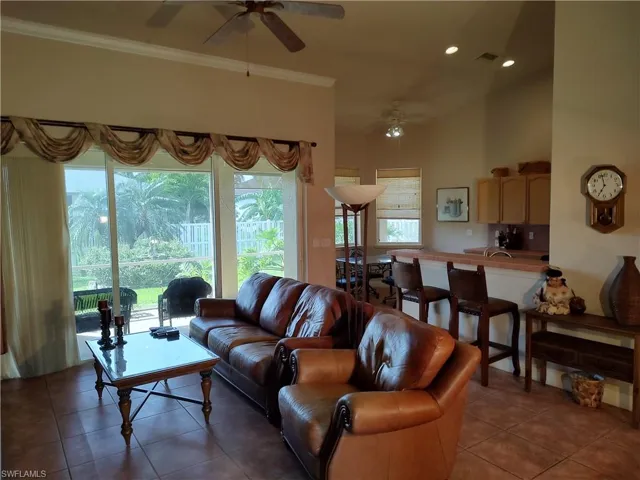 Tiled living room with ornamental molding, a wealth of natural light, and ceiling fan