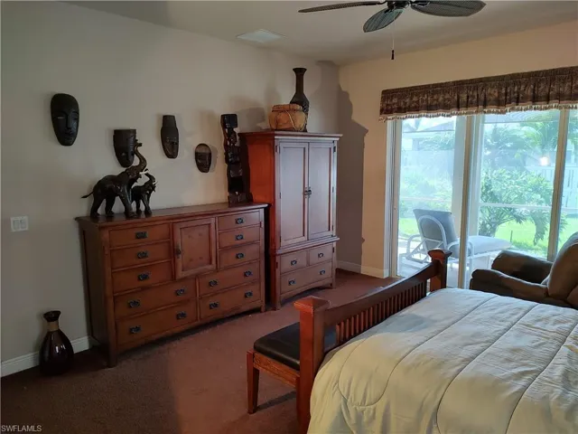 Bedroom with access to exterior, dark carpet, and ceiling fan