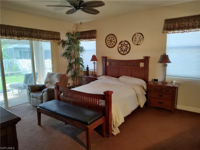 Carpeted bedroom with ceiling fan, access to exterior, and multiple windows