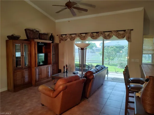 Living room featuring crown molding, light tile patterned floors, and ceiling fan