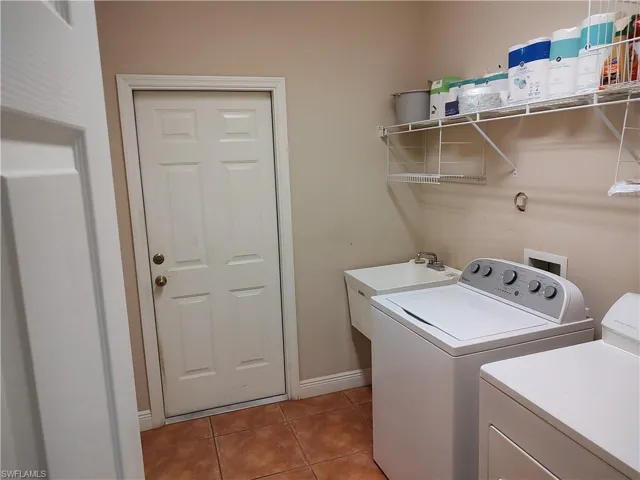 Laundry area featuring sink, washer and clothes dryer, and tile patterned flooring