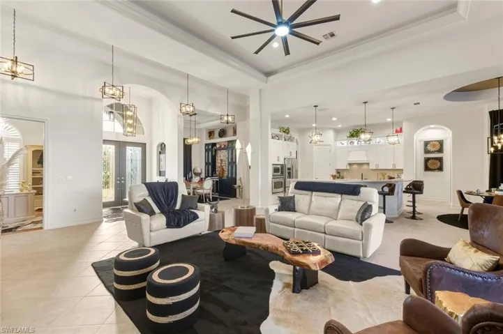 Living area with arched walkways, a chandelier, a tray ceiling, a towering ceiling, and light tile patterned floors