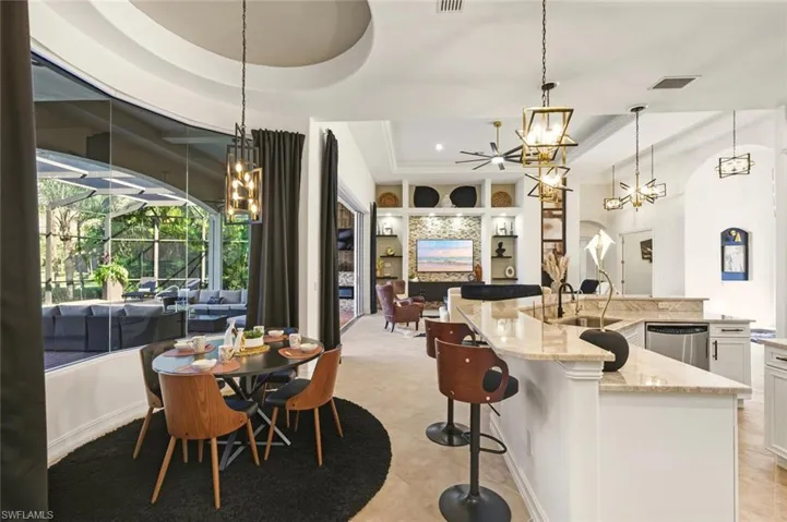 Kitchen with a chandelier, a breakfast bar area, white cabinets, and light stone countertops