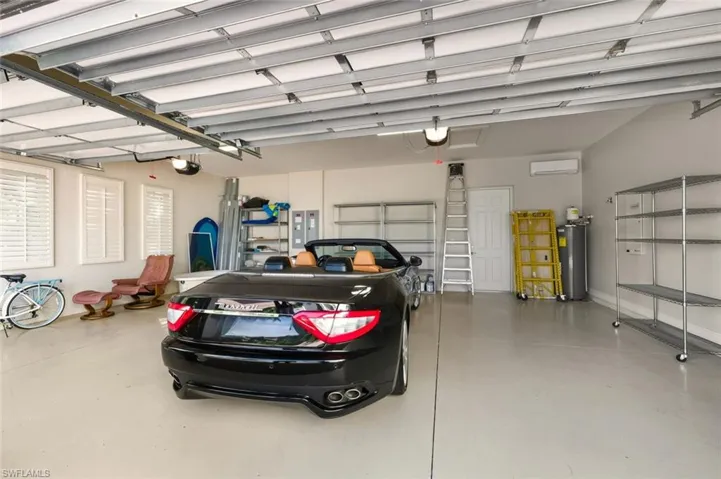Garage with water heater, a wall mounted air conditioner, and electric panel