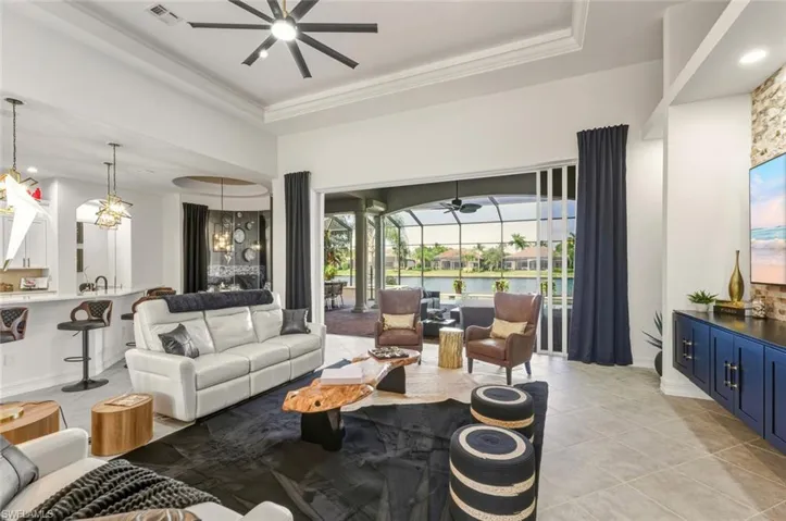 Living room featuring a sunroom, a raised ceiling, a ceiling fan, recessed lighting, and light tile patterned flooring