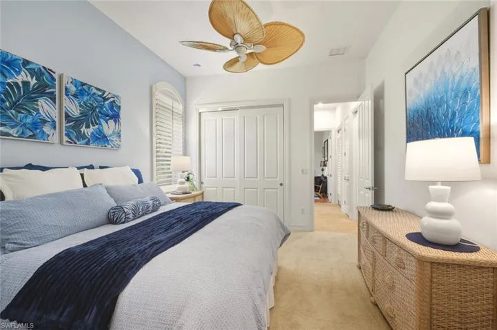 Bedroom with light carpet, ceiling fan, and a closet