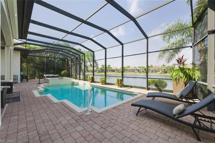View of swimming pool featuring a sunroom, a lanai, a patio area, a water view, and a pool with connected hot tub