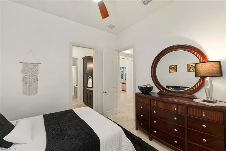 Bedroom with ceiling fan, light carpet, and ensuite bath