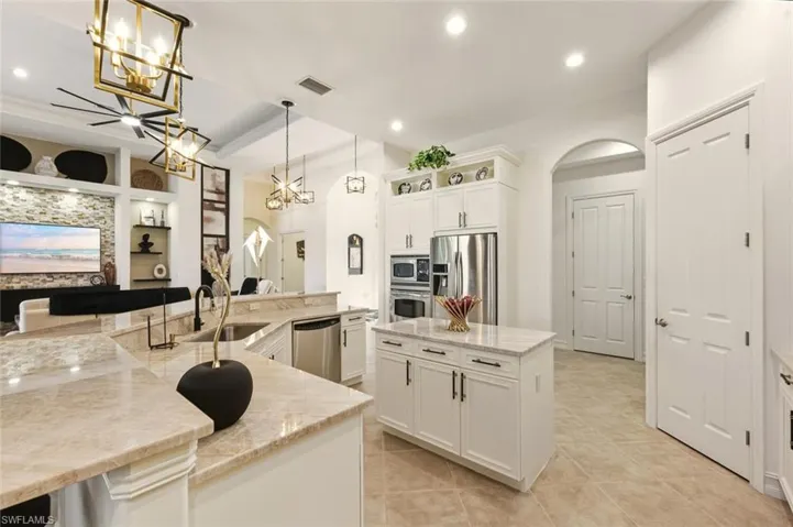 Kitchen with pendant lighting, built in shelves, arched walkways, light stone counters, and appliances with stainless steel finishes