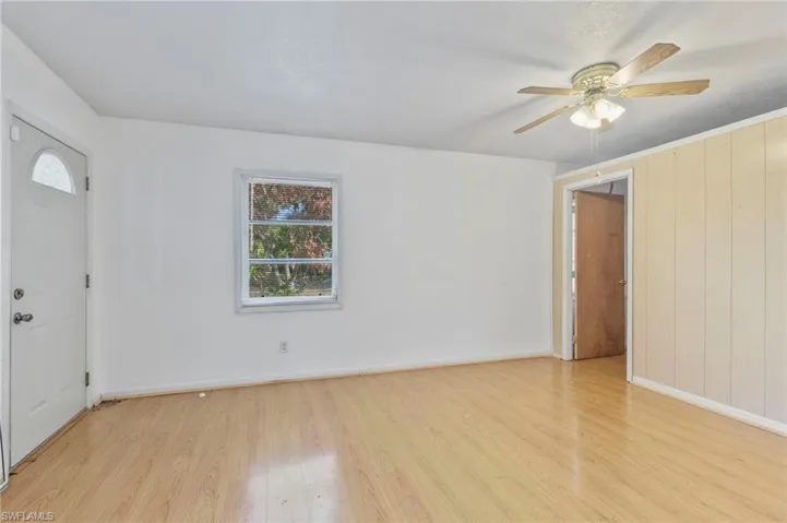 Entrance foyer with light wood-style flooring, ceiling fan, and wooden walls