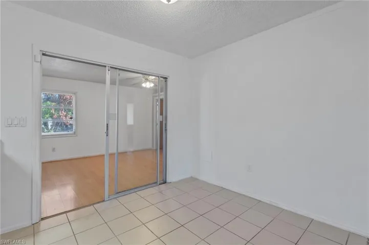 Empty room featuring a textured ceiling, light tile patterned floors, and ceiling fan