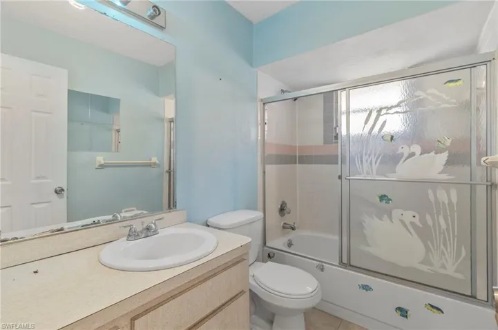 Bathroom with vanity, shower / bath combination with glass door, and light tile patterned floors