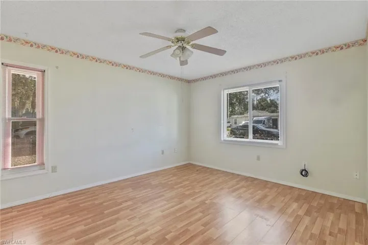 Empty room with light wood-style flooring, a textured ceiling, and a ceiling fan