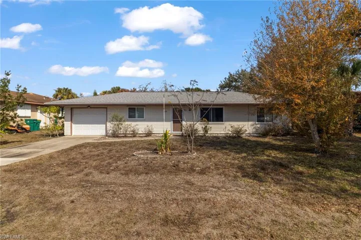 Ranch-style house featuring a garage, concrete driveway, and a front yard