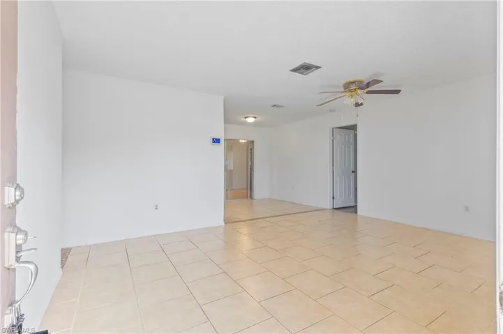 Empty room with a ceiling fan and light tile patterned floors