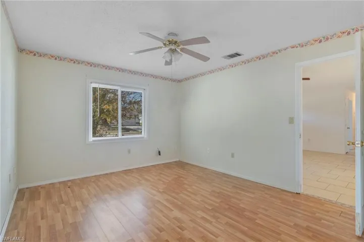 Empty room with light wood-type flooring, ceiling fan, and a textured ceiling