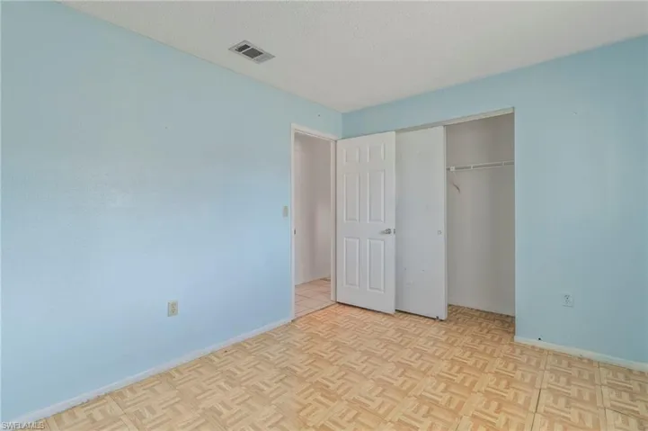 Unfurnished bedroom with a textured ceiling, a closet, and parquet flooring