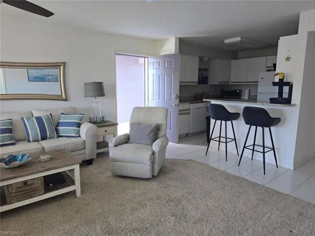 Living area with light tile patterned floors and light colored carpet