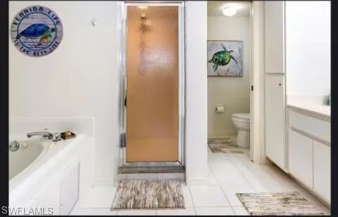 Bathroom featuring light tile patterned flooring, a bath, vanity, and a stall shower