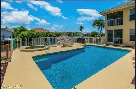 View of pool with an in-ground hot tub, a patio area, and a balcony