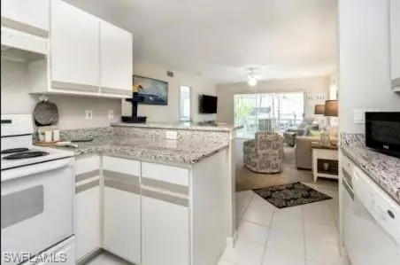 Kitchen with white appliances, a peninsula, white cabinets, and open floor plan