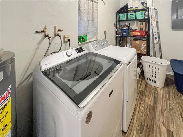 Laundry room with electric water heater, washer and dryer, electric panel, and hardwood / wood-style floors