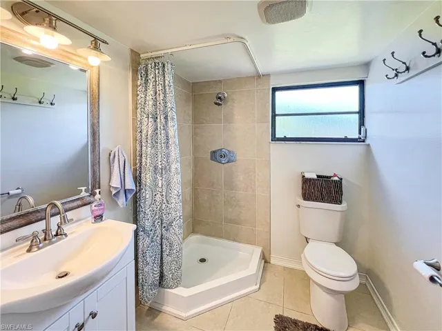 Bathroom featuring tile patterned floors, vanity, a shower with curtain, and toilet