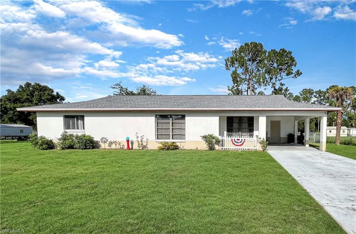 Single story home featuring a carport and a front lawn