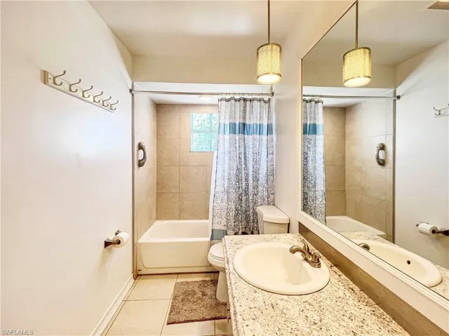 Full bathroom with vanity, toilet, tile patterned flooring, and shower / bath combo
