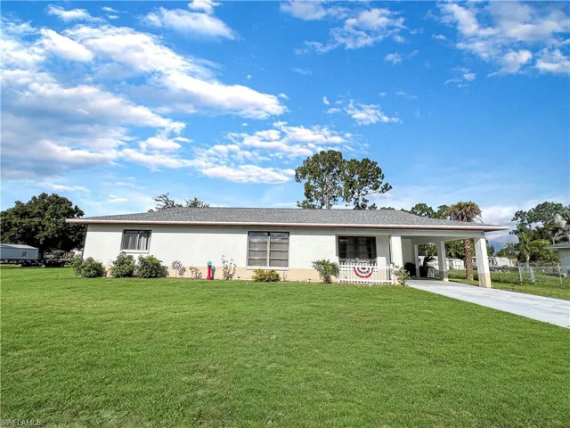 Ranch-style house with a carport and a front lawn