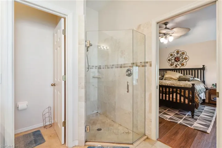 Bathroom with wood-type flooring, ceiling fan, and an enclosed shower