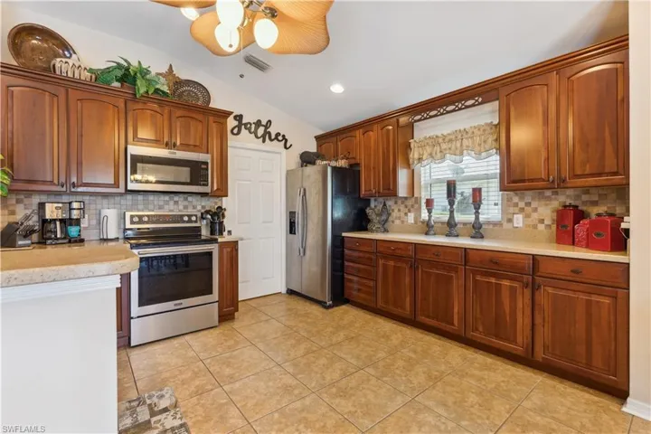 Kitchen featuring ceiling fan, stainless steel appliances, backsplash, and lofted ceiling