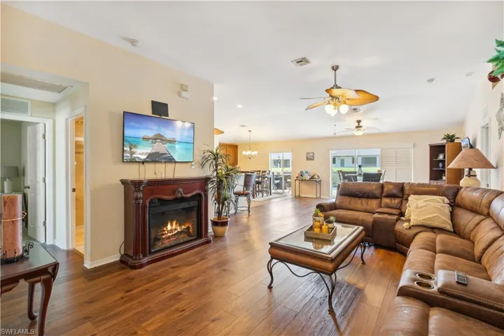 Living room with ceiling fan with notable chandelier and hardwood / wood-style floors