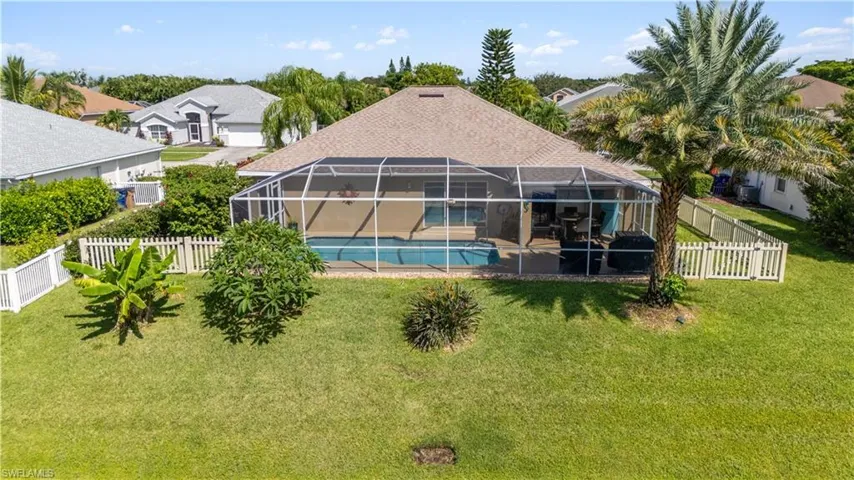 Rear view of property featuring glass enclosure, a yard, and a fenced in pool