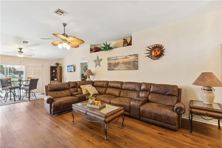 Living room featuring vaulted ceiling, hardwood / wood-style floors, and ceiling fan