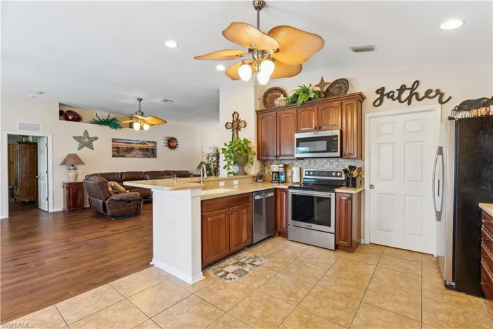 Kitchen with ceiling fan, sink, kitchen peninsula, stainless steel appliances, and light wood-type flooring
