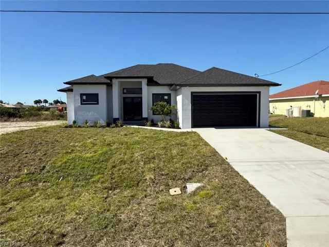 View of front of home with a garage and a front lawn