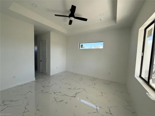 Unfurnished room with a tray ceiling and ceiling fan