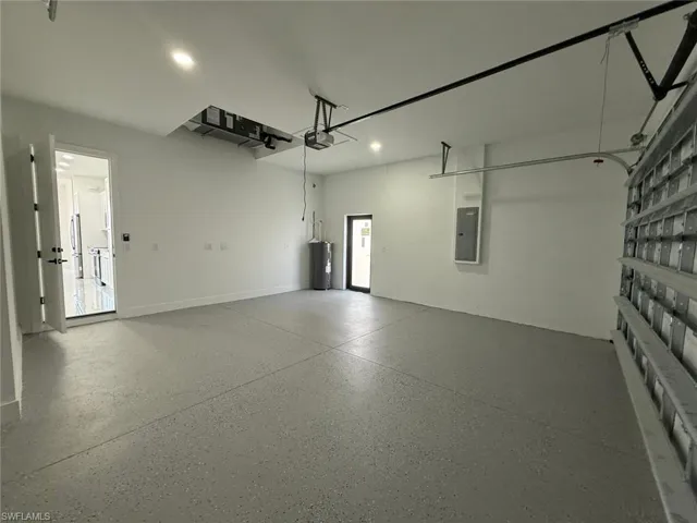 Garage featuring a garage door opener, electric panel, and electric water heater