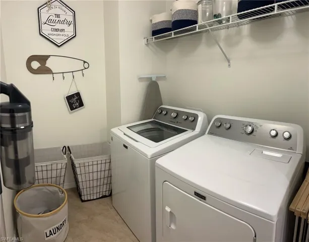 Washroom with independent washer and dryer and light tile patterned floors