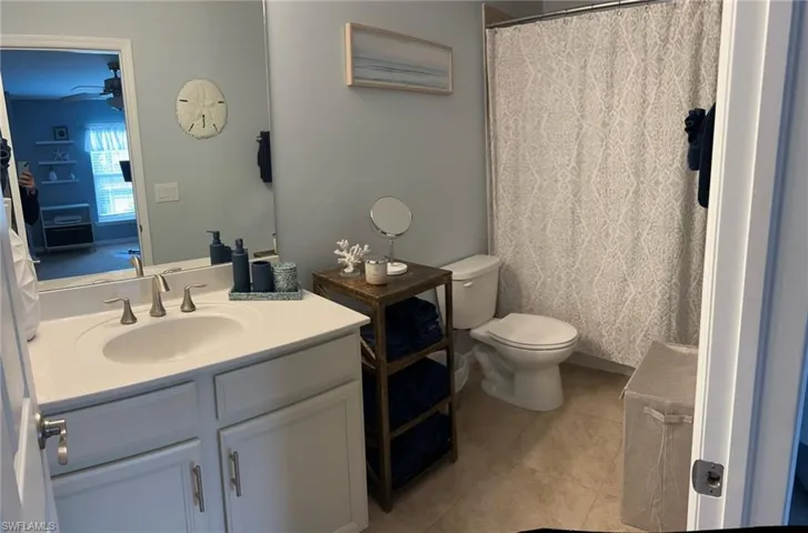 Bathroom with vanity, tile patterned floors, ceiling fan, and toilet