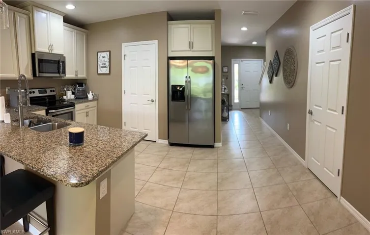 Kitchen featuring a breakfast bar area, light tile patterned floors, kitchen peninsula, appliances with stainless steel finishes, and stone counters