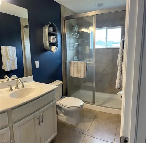 Bathroom featuring vanity, toilet, walk in shower, and tile patterned flooring