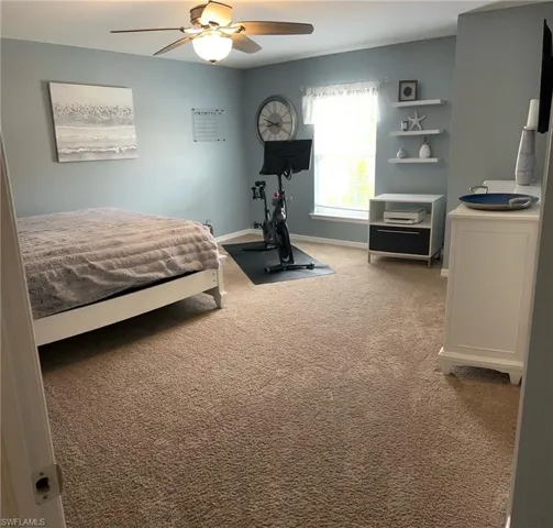 Carpeted bedroom featuring ceiling fan