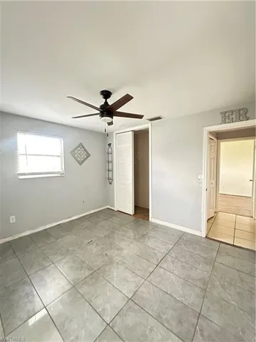 Empty room with light tile patterned floors and a ceiling fan