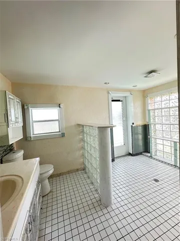 Bathroom with a textured wall, vanity, plenty of natural light, and light tile patterned floors