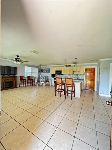 Dining area featuring a fireplace, ornamental molding, light tile patterned floors, and ceiling fan