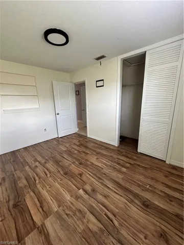 Unfurnished bedroom with dark wood finished floors and a closet