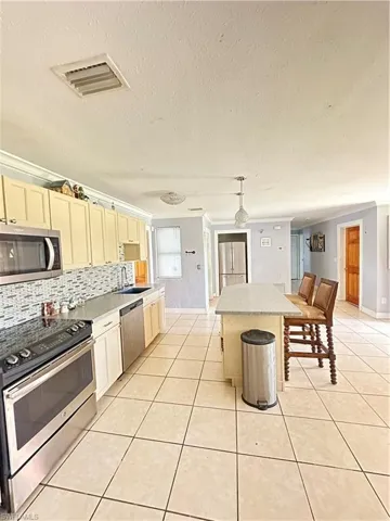 Kitchen with range, light tile patterned floors, a textured ceiling, light countertops, and hanging light fixtures